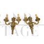 Pair of baroque style wall lights in golden brass                            